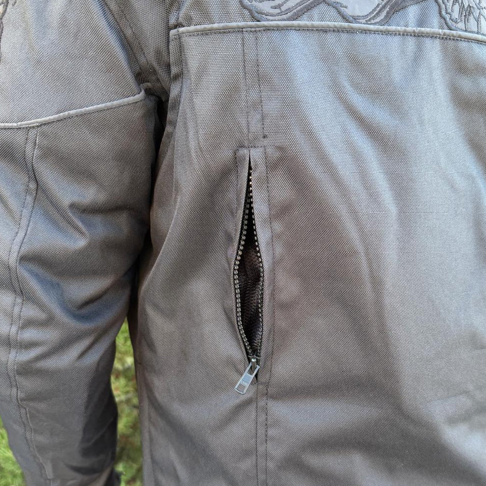 A man wearing a black bomber motorcycle jacket with intricate black embroidery across the chest