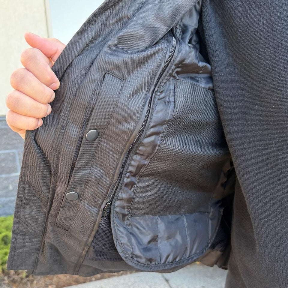 A man wearing a black bomber motorcycle jacket with intricate black embroidery across the chest