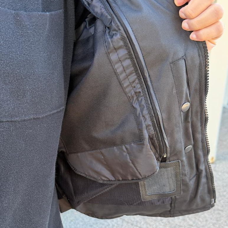 A man wearing a black bomber motorcycle jacket with intricate black embroidery across the chest