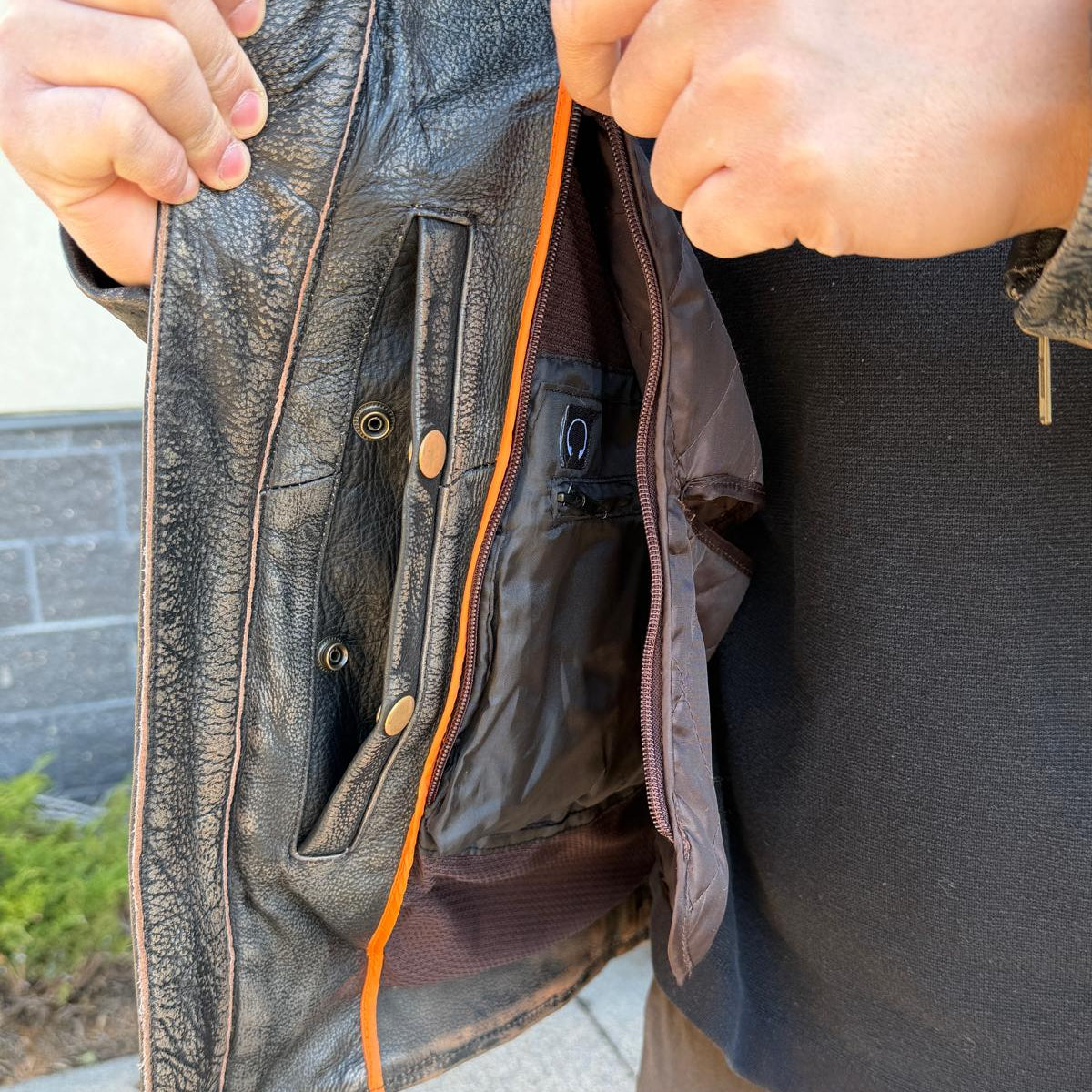 A man wearing a distressed brown leather motorcycle jacket with geometric diamond-stitch detailing on the shoulders