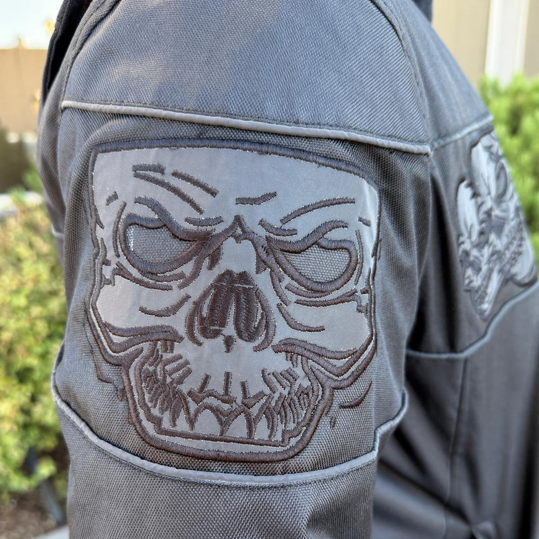 A man wearing a black bomber motorcycle jacket with intricate black embroidery across the chest