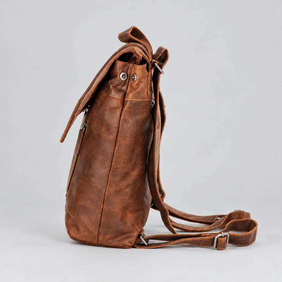 A brown leather backpack shown from a side profile view