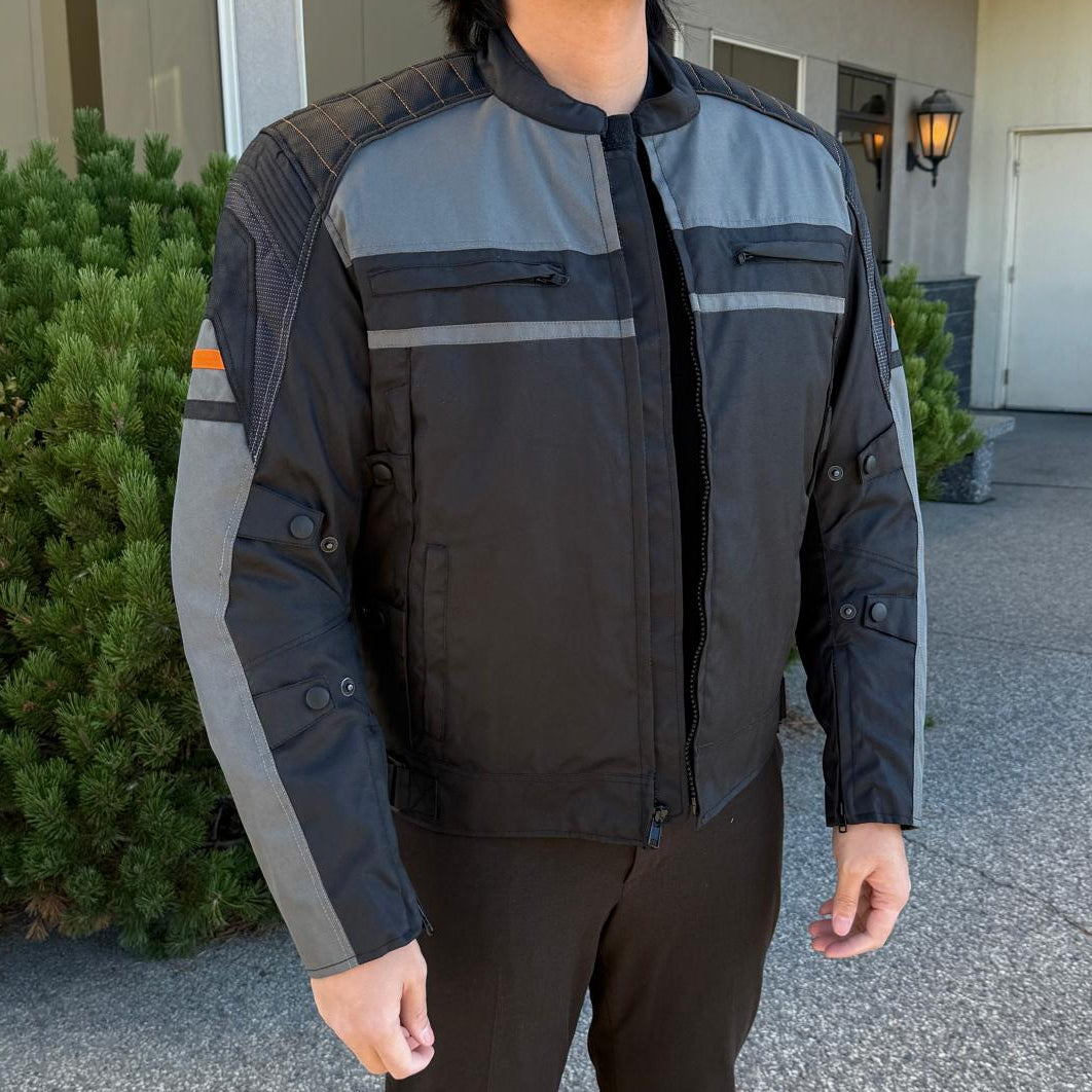 A man wearing a black and gray motorcycle jacket with reflective gray stripes