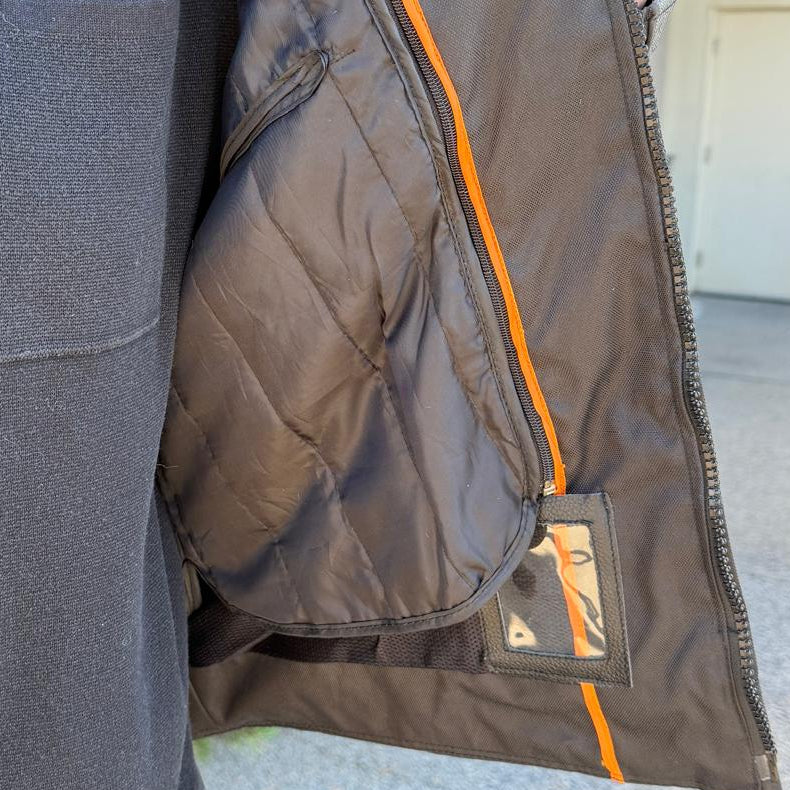 A man wearing a black and gray motorcycle jacket with reflective gray stripes