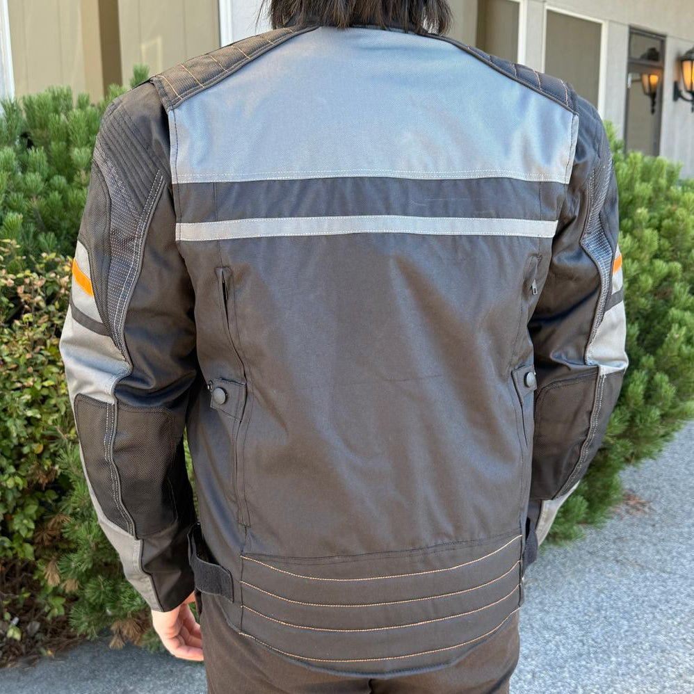 A man wearing a black and gray motorcycle jacket with reflective gray stripes