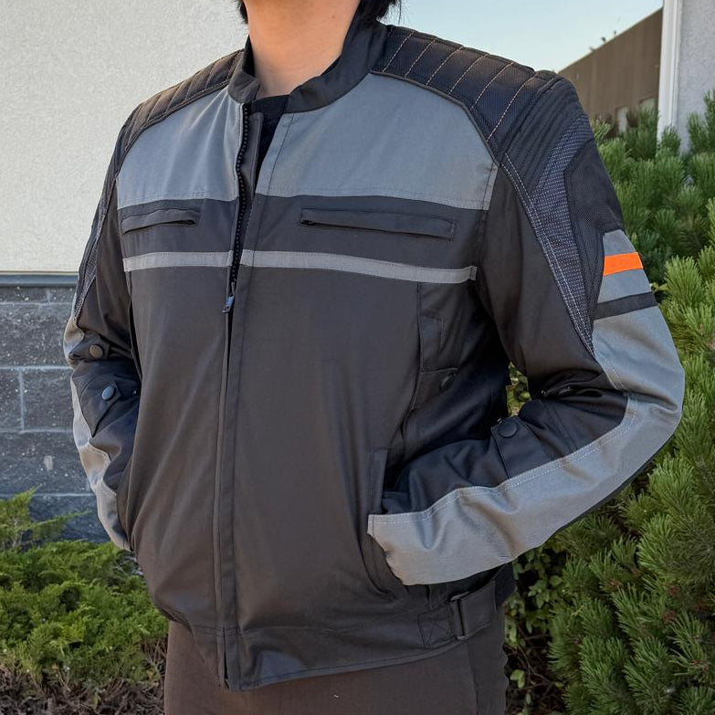 A man wearing a black and gray motorcycle jacket with reflective gray stripes