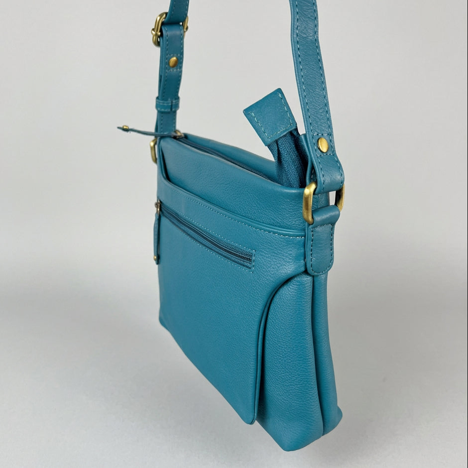A teal blue pebbled leather crossbody bag with gold-tone hardware
