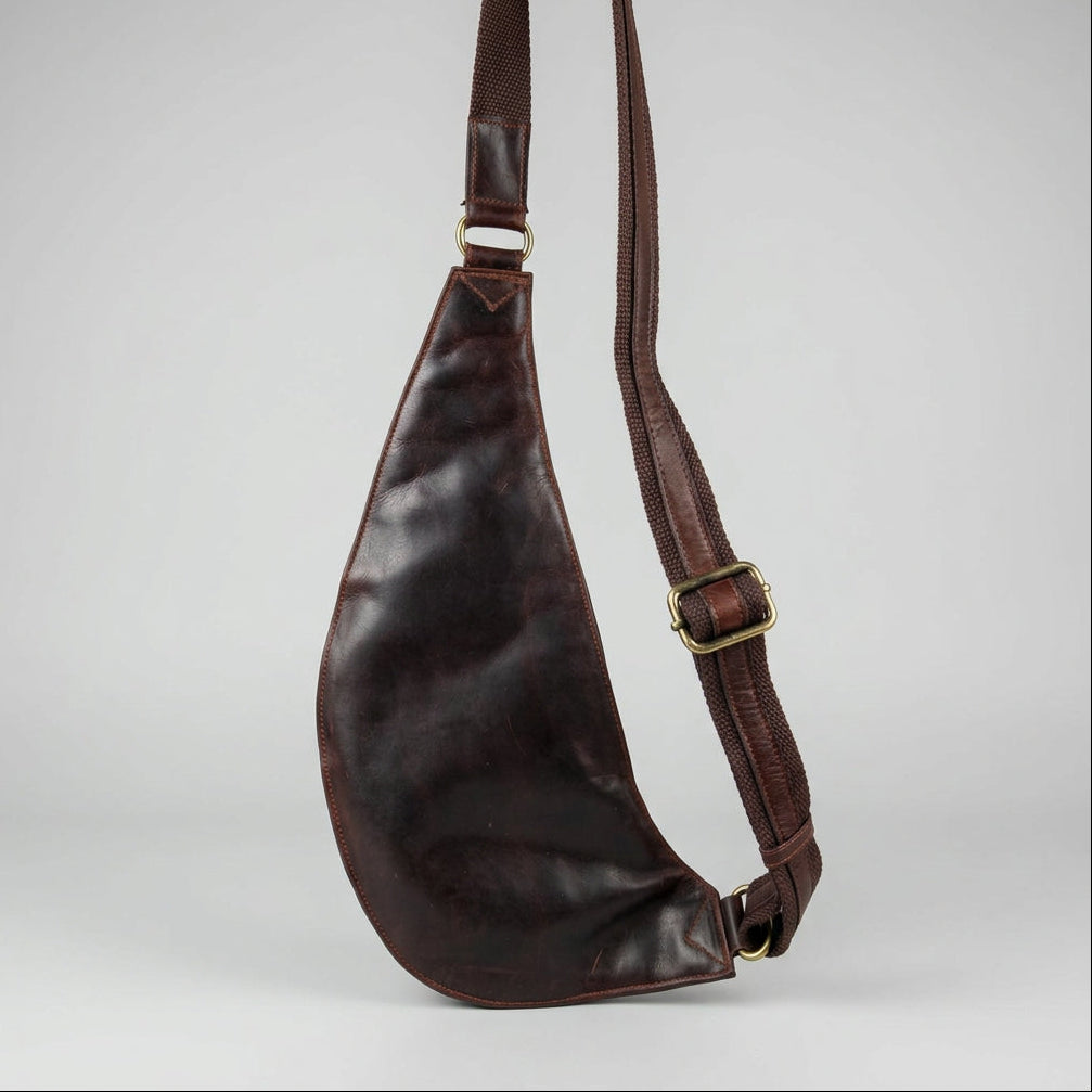 A dark brown leather shoulder bag with a wide adjustable strap and brass-tone buckle