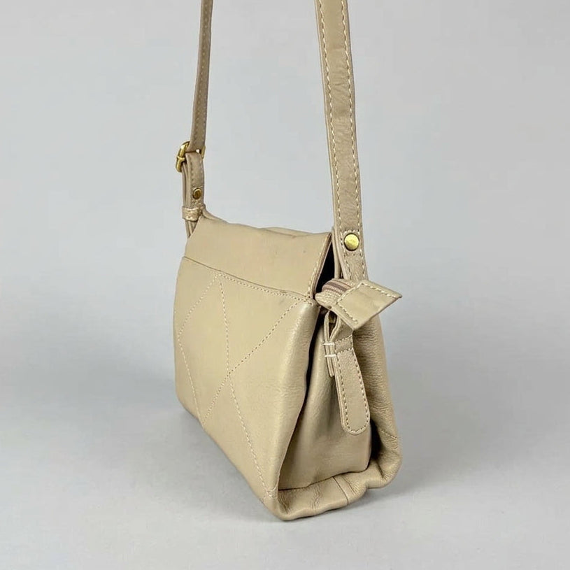 A small beige crossbody bag with a matching strap and gold-tone hardware