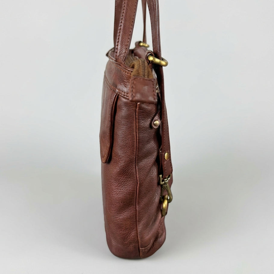 A brown leather shoulder bag shown from the side, featuring brass-tone hardware and a slouchy silhouette