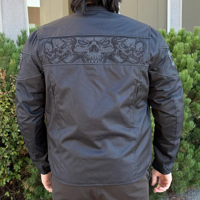 A man wearing a black bomber motorcycle jacket with intricate black embroidery across the chest