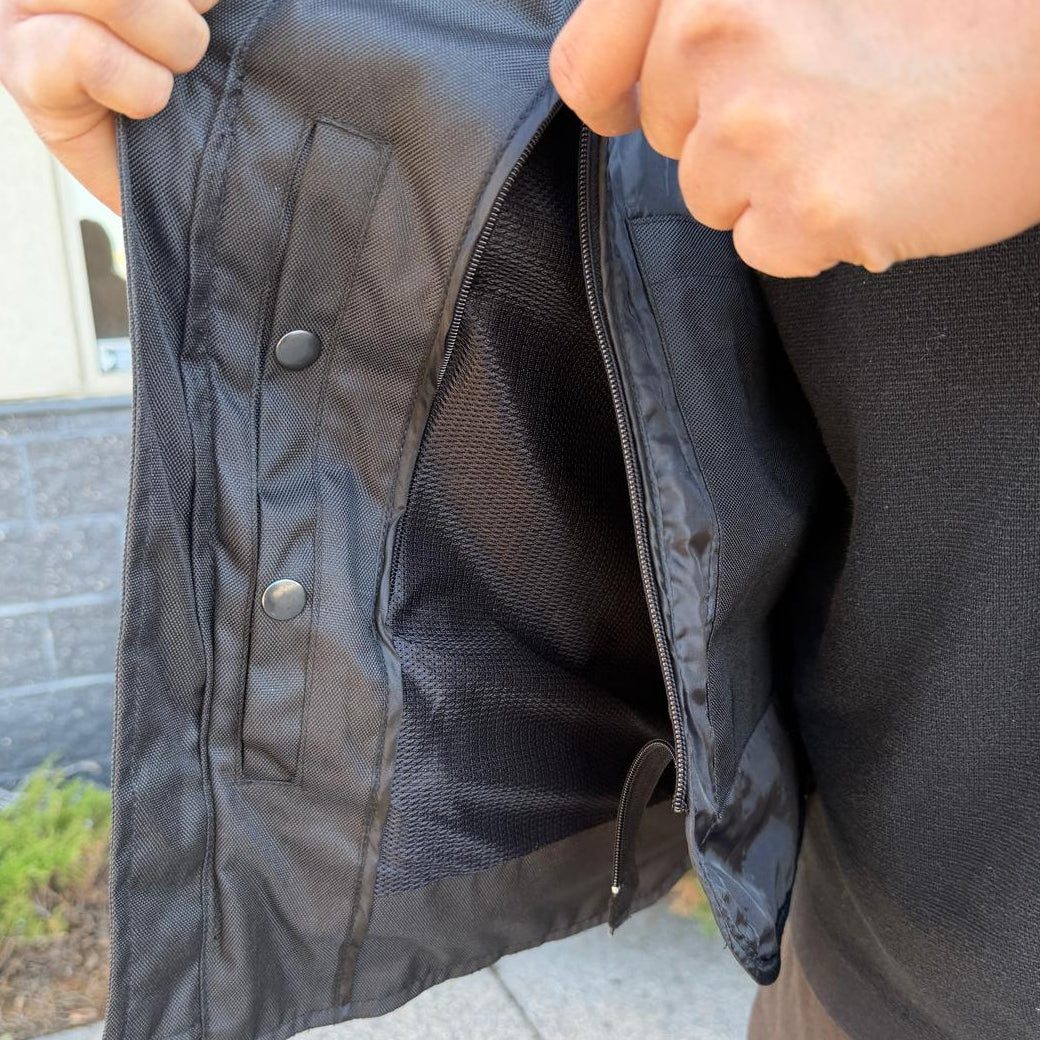 A man wearing a black bomber motorcycle jacket with intricate black embroidery across the chest