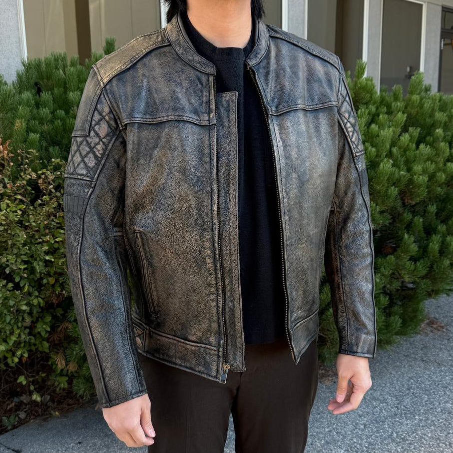 A man wearing a distressed brown leather motorcycle jacket with geometric diamond-stitch detailing on the shoulders