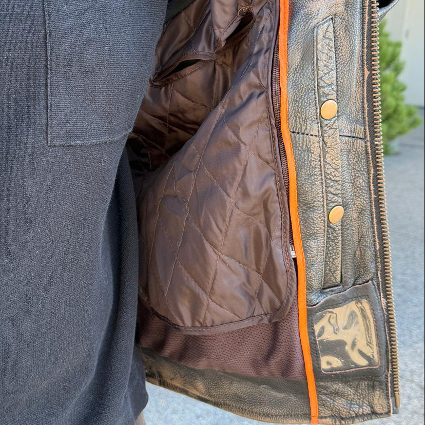 A man wearing a distressed brown leather motorcycle jacket with geometric diamond-stitch detailing on the shoulders