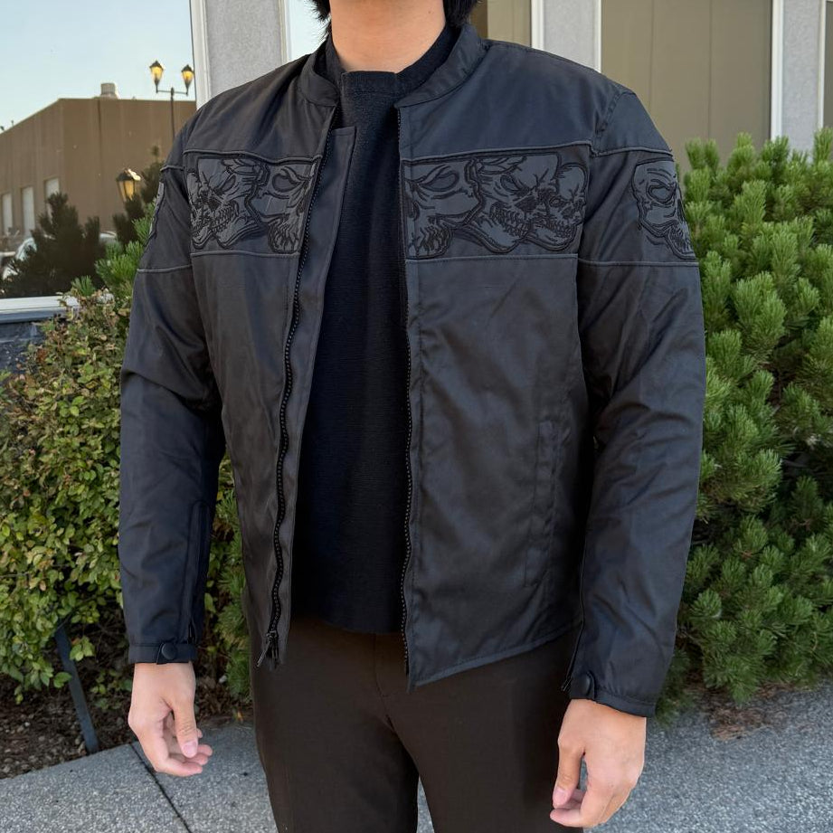A man wearing a black bomber motorcycle jacket with intricate black embroidery across the chest