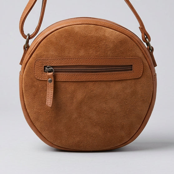 A round brown suede crossbody bag with a front zippered pocket, shown against a plain white background.