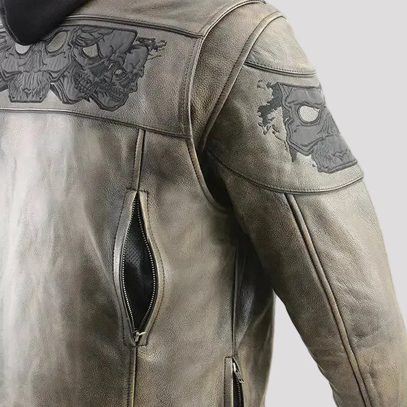 A distressed brown leather motorcycle jacket with a black hood, featuring skull graphics on the shoulders and a side zip pocket, shown on a white background.