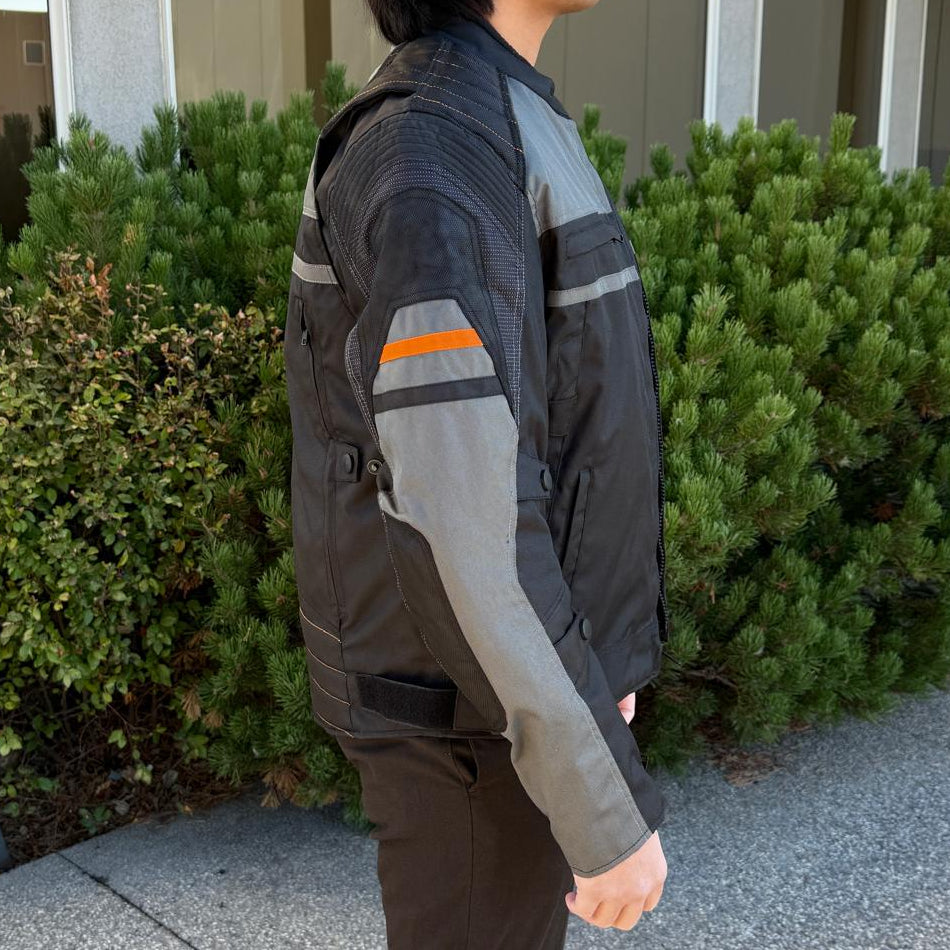 A man wearing a black and gray motorcycle jacket with reflective gray stripes