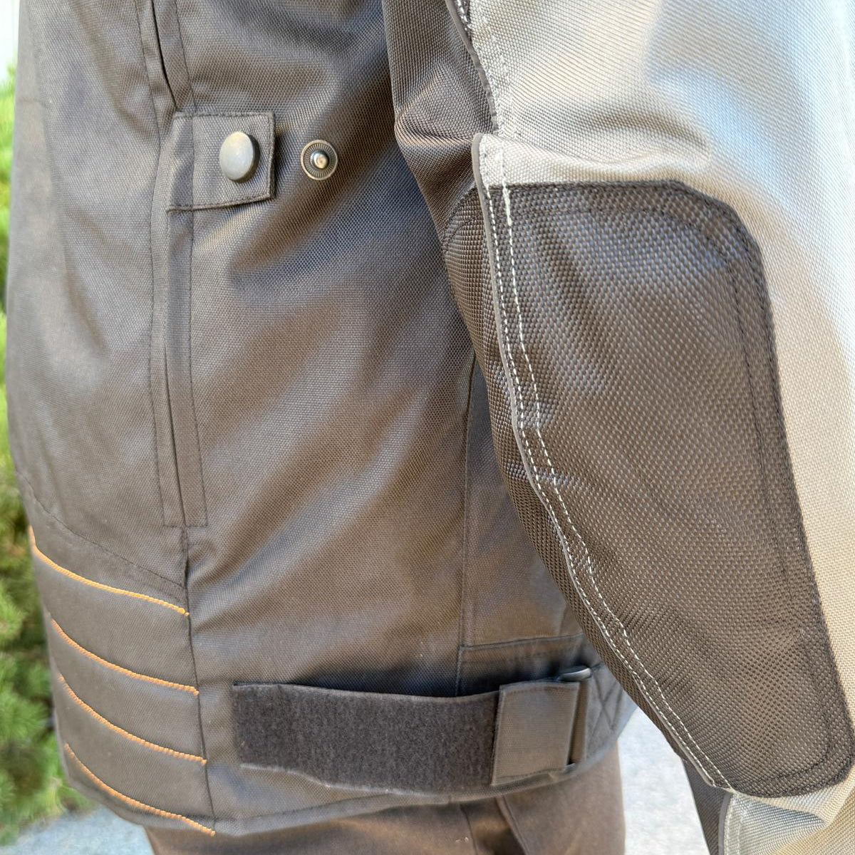 A man wearing a black and gray motorcycle jacket with reflective gray stripes