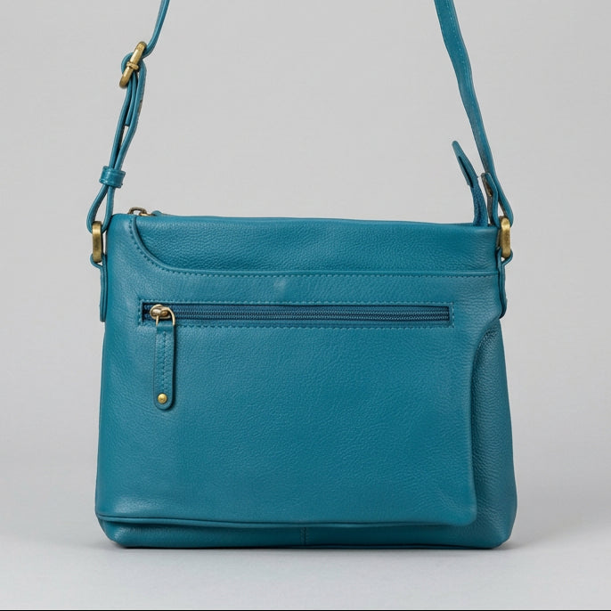 A teal blue pebbled leather crossbody bag with gold-tone hardware, featuring a front zippered pocket and a top zip closure