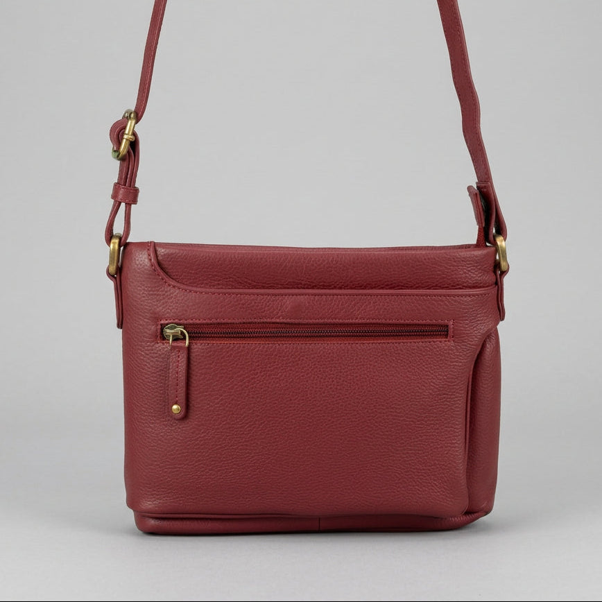 A burgundy pebbled leather crossbody bag with a front zippered pocket and gold-tone hardware