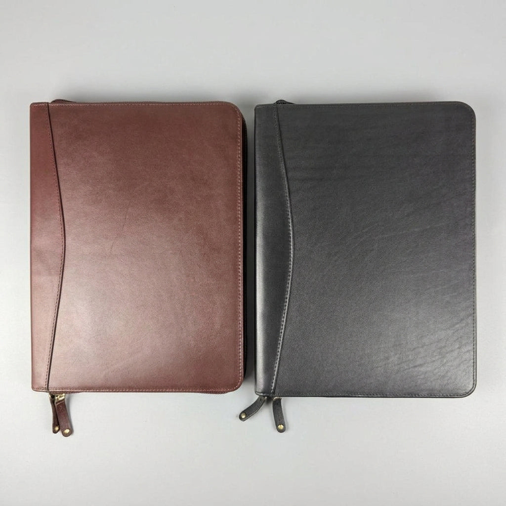 Two zip-around leather planner covers, one in reddish-brown and one in dark charcoal gray