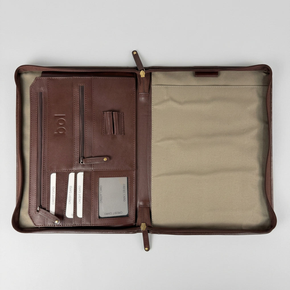 An open brown leather organizer pouch or document holder with a beige fabric interior, laid flat on a gray wood-textured surface. The left side shows card slots, zip compartments, and a small embossed logo reading 'bol'.