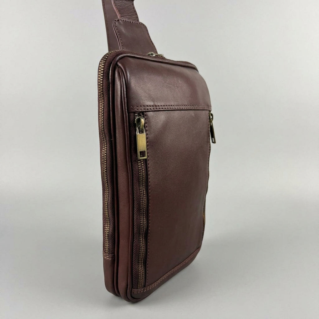 A dark brown leather crossbody phone bag with gold-tone zippers