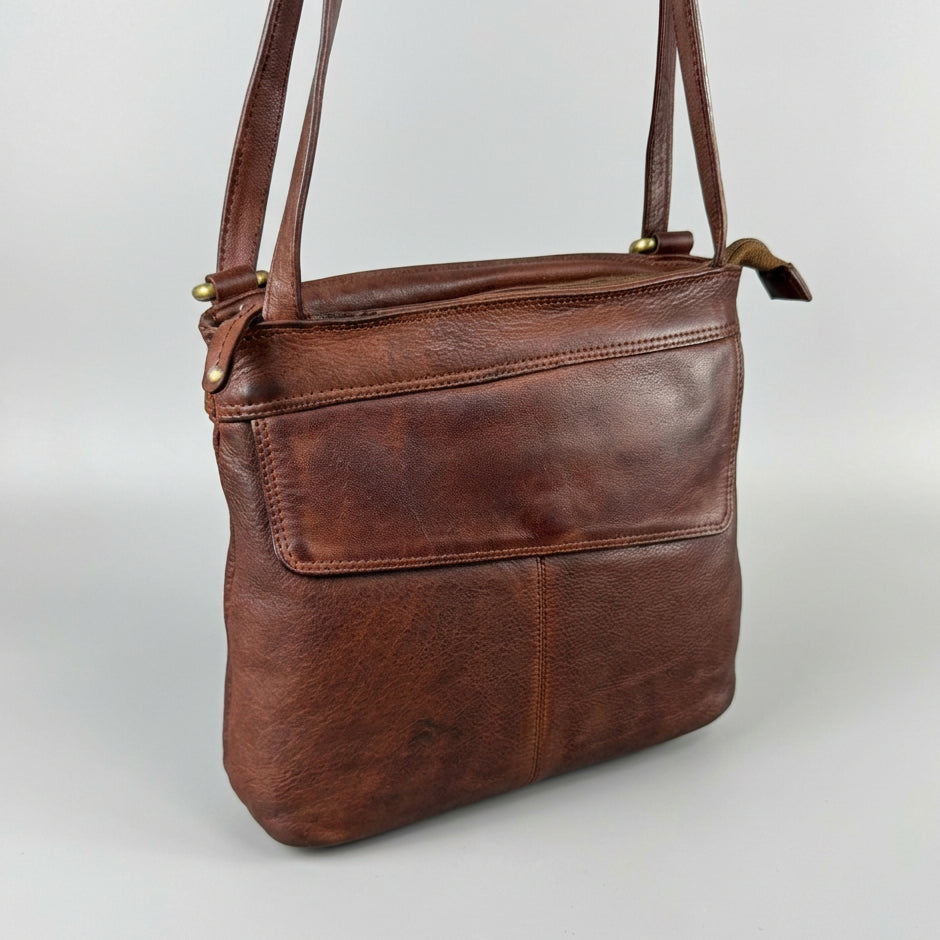 A brown leather bag with a front pocket and shoulder strap